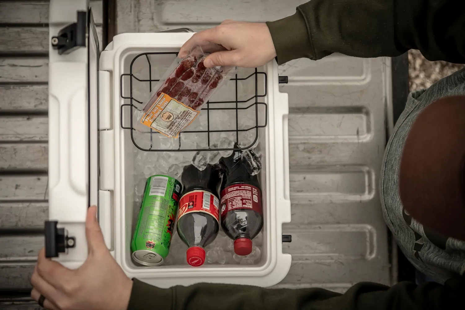 person putting drinks and food in cooler with basket